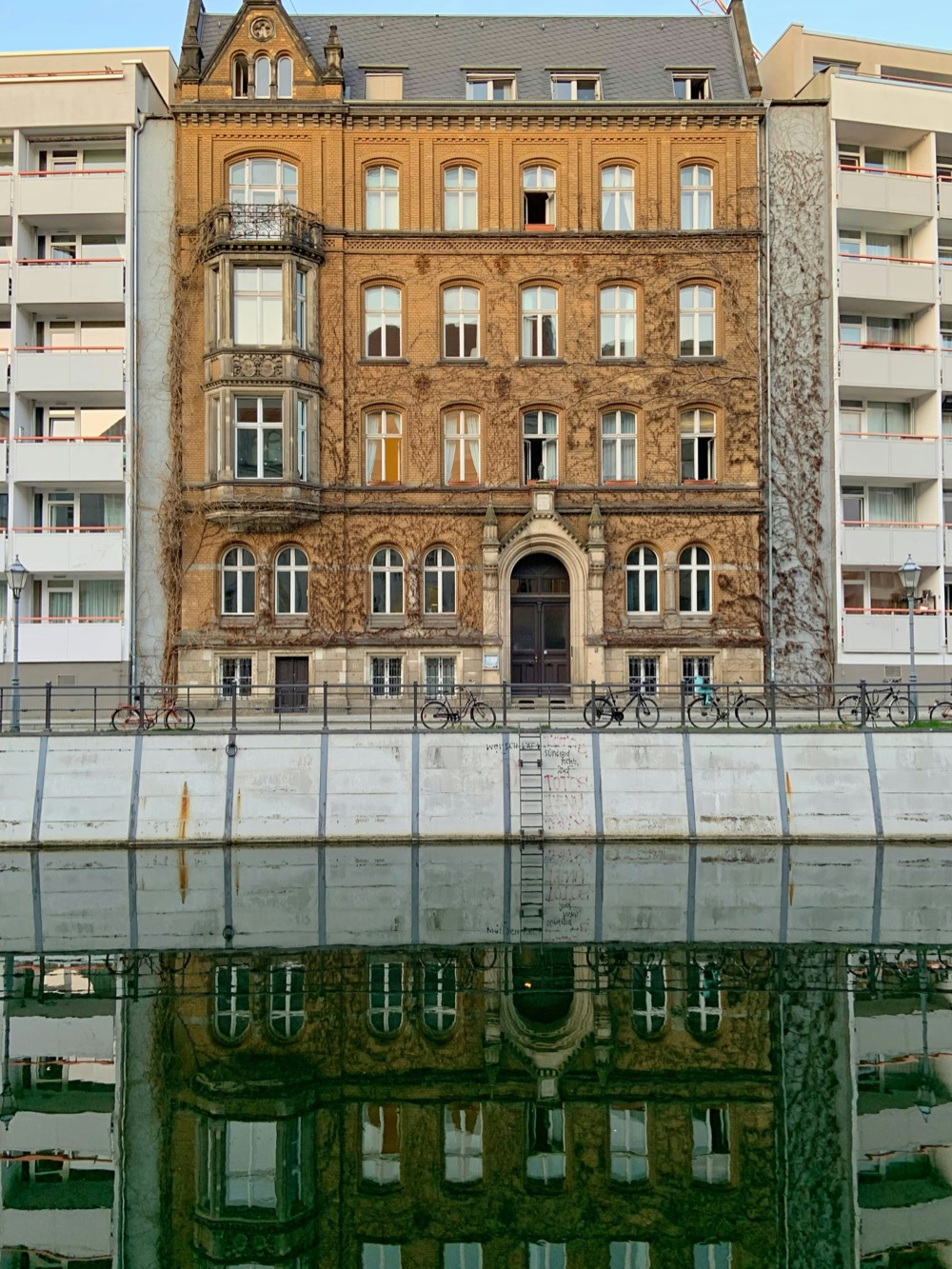 Berliner Altbau mit Klinkerfassade, eingeklemmt zwischen zwei Plattenbauten am Wasser